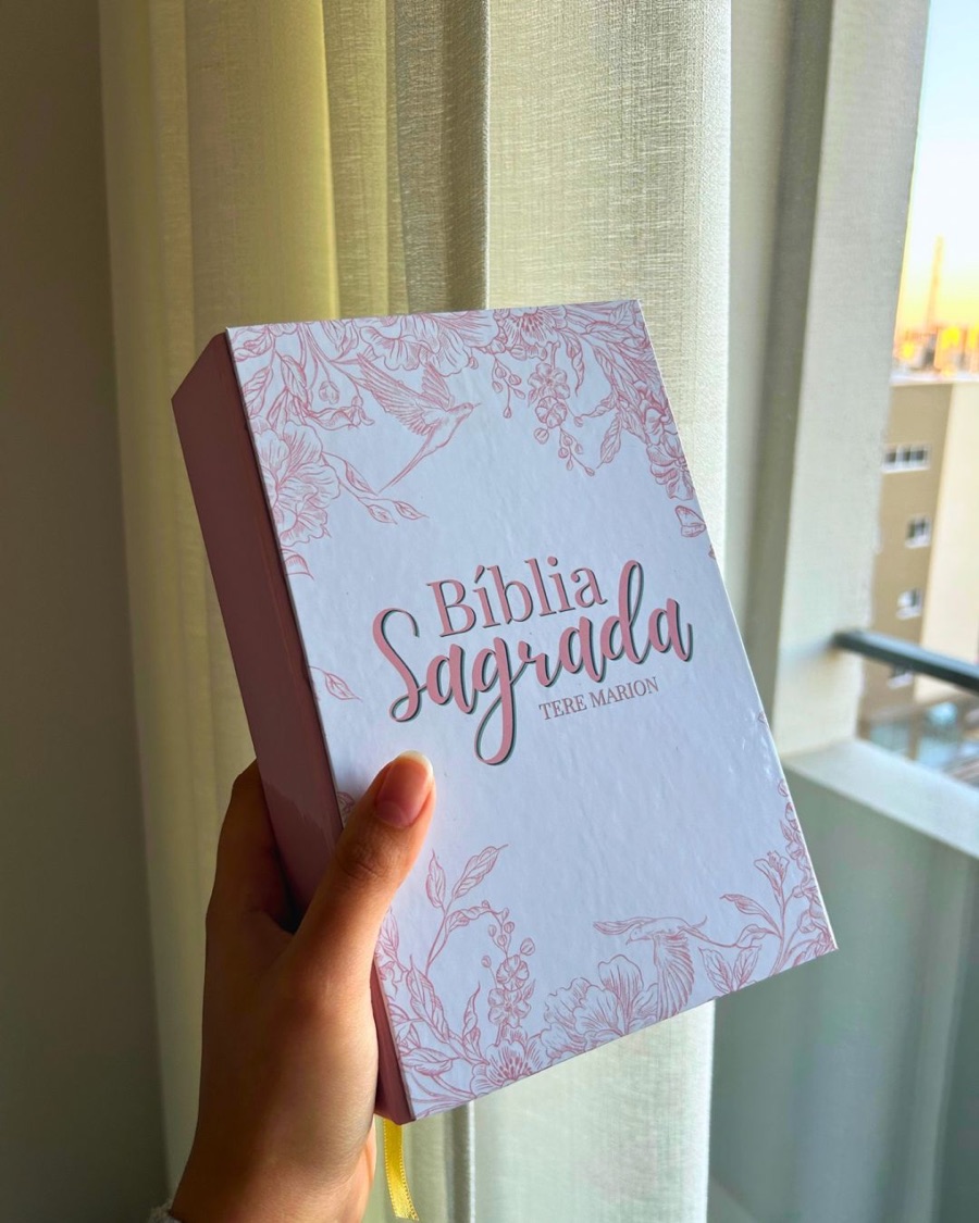 Bíblia Sagrada com capa personalizada em tom rosado, ilustração floral e o nome da cliente impresso.